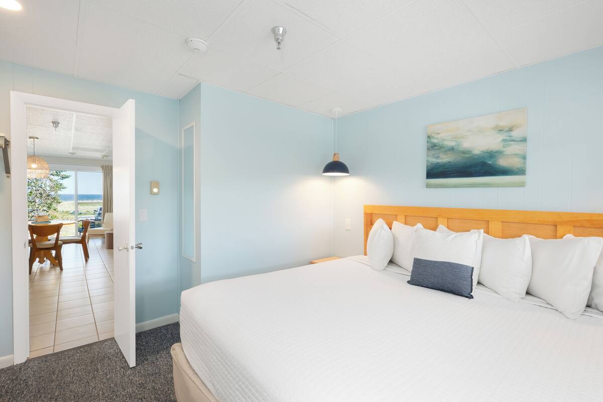 Een slaapkamer met een bed, een schilderij en uitzicht op de omgeving.