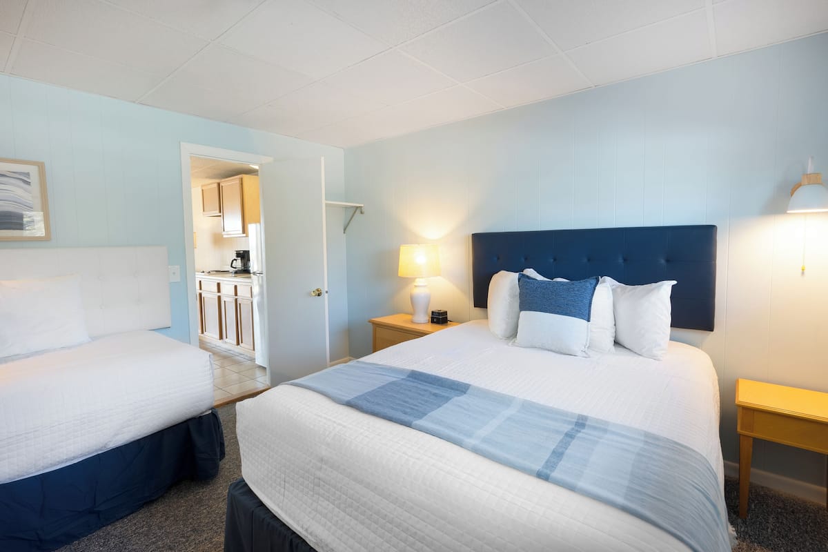 Een hotelkamer met twee bedden, een kitchenette en een badkamer die door een open deur zichtbaar is.