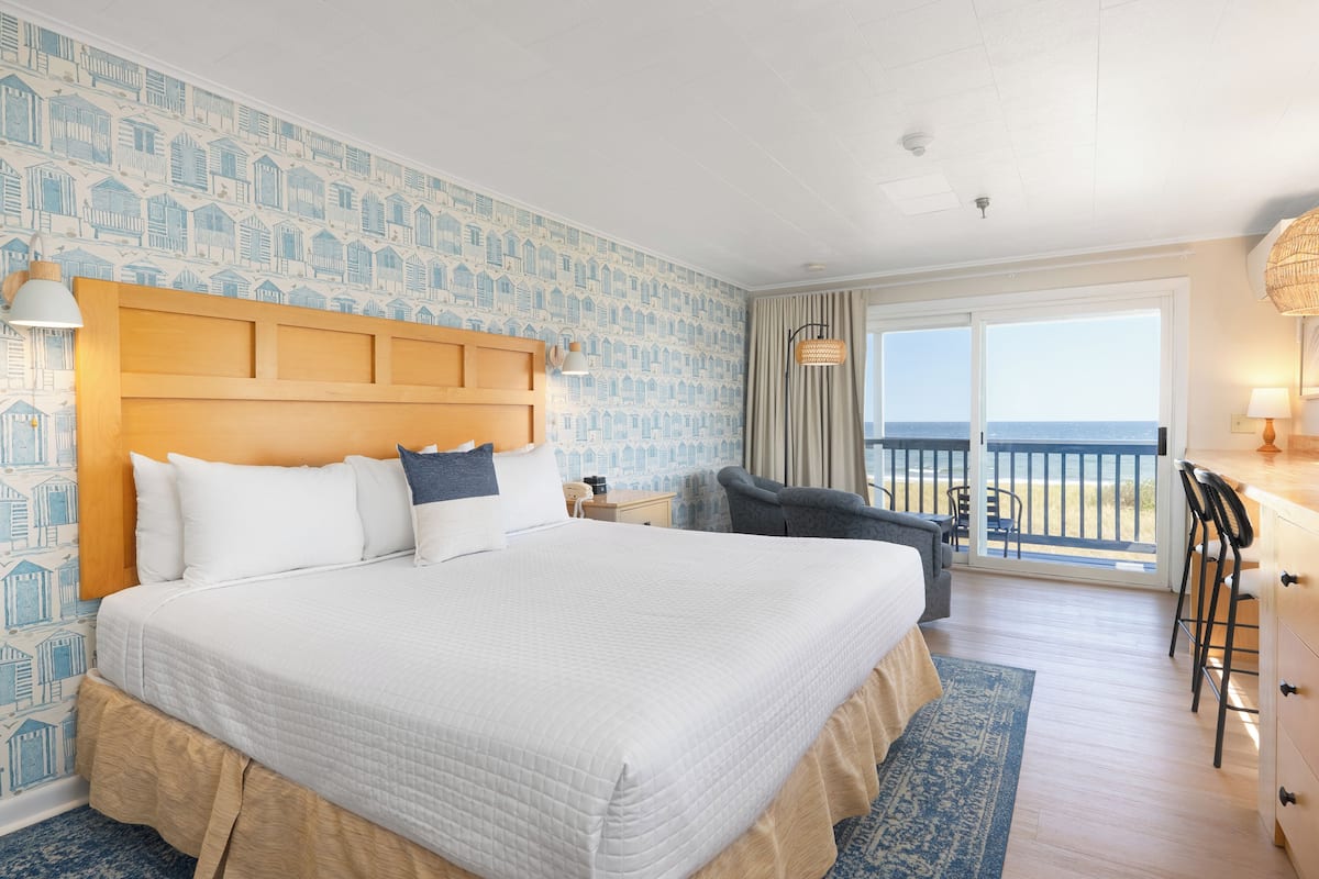 Een hotelkamer met een groot bed, een balkon met uitzicht en een bureau met stoel.