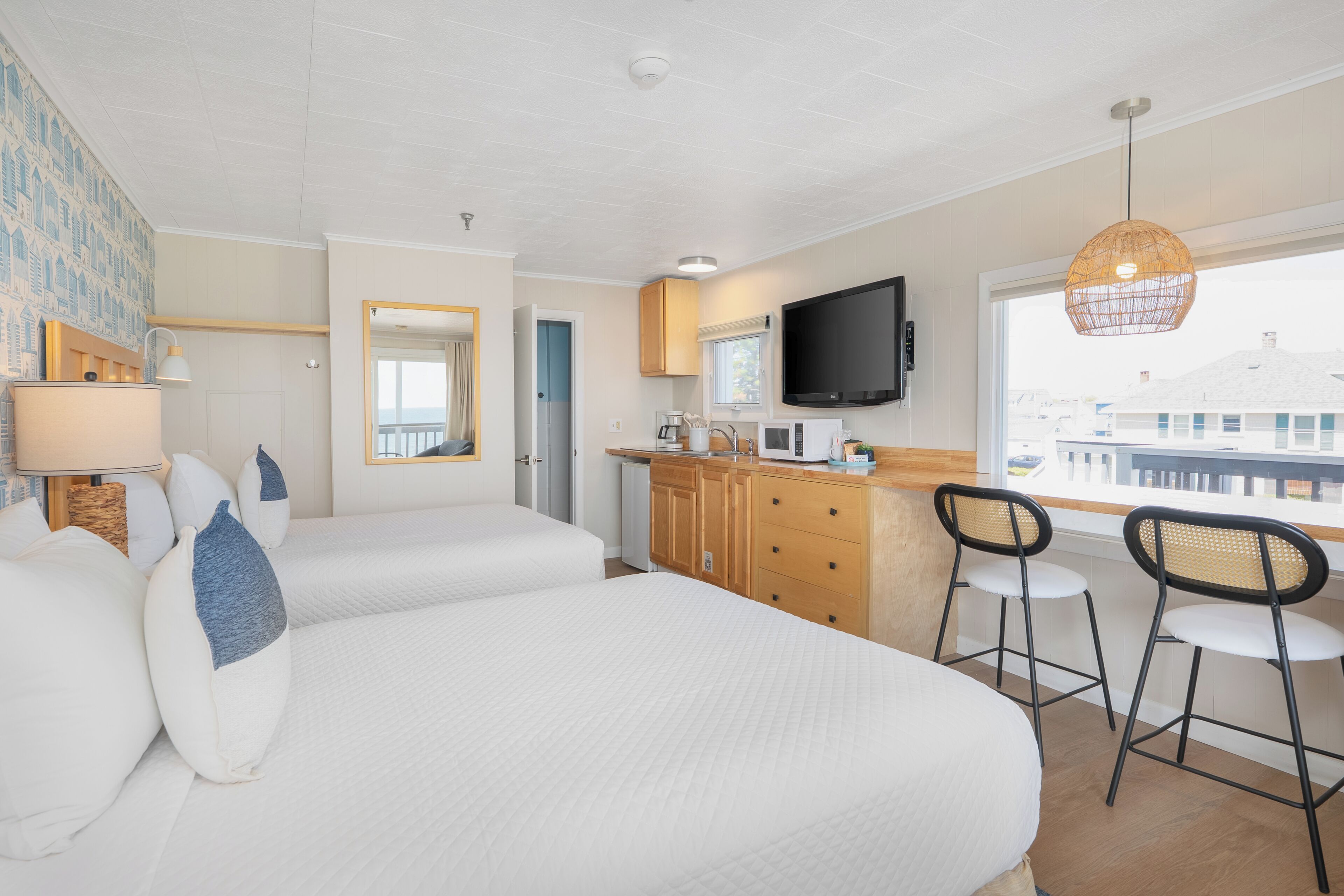 Une chambre d’hôtel avec deux lits, une kitchenette, une télévision et une grande fenêtre.