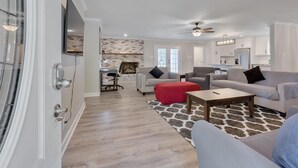 A modern living room with a fireplace, a dining area, and a kitchen.