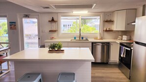 Een moderne keuken met een centraal eiland, roestvrijstalen apparatuur en uitzicht op de omgeving.