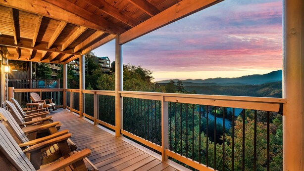 A wooden deck with chairs overlooking a scenic landscape.
