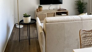 A modern living room with a flat-screen TV, a sofa, a coffee table, and a floor lamp.