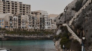 A coastal view with a rocky cliff and a staircase leading up to a building.