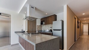 A modern kitchen with a granite countertop, stainless steel appliances, and wooden cabinetry. - Roma Sur Apartments by VH (Mexico City)