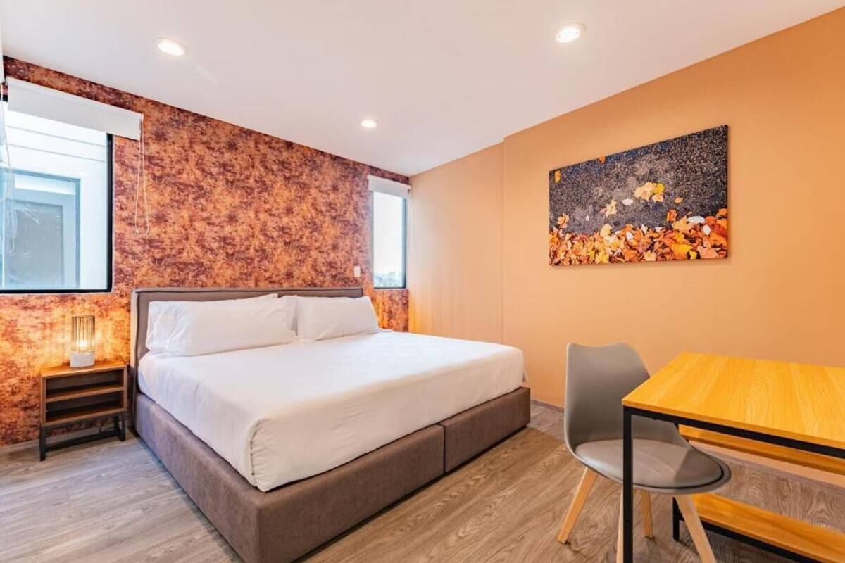 Een moderne slaapkamer met een groot bed, een houten tafel en een stoel.