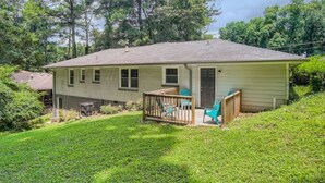 A single-story house with a covered porch, a small deck, and a well-maintained lawn.