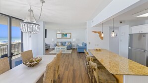 Eine moderne Küche mit einer Granit Arbeitsplatte, Holzbarhocker und einem Essbereich mit weißem Tisch und Korbstühlen.