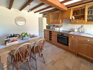 A kitchen with wooden cabinets, a microwave, an oven, and a dining table with chairs. - Holiday home for 4 people, breath taking scenery, bike storage, WiFi & only a short walk to the pub. (Richmond)