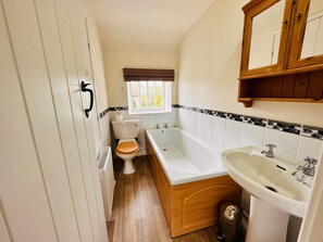 A compact bathroom with a toilet, a bathtub, and a sink. - Holiday home for 4 people, breath taking scenery, bike storage, WiFi & only a short walk to the pub. (Richmond)