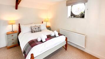 Een slaapkamer met een bed, twee nachtkastjes, een raam met uitzicht en een radiator.