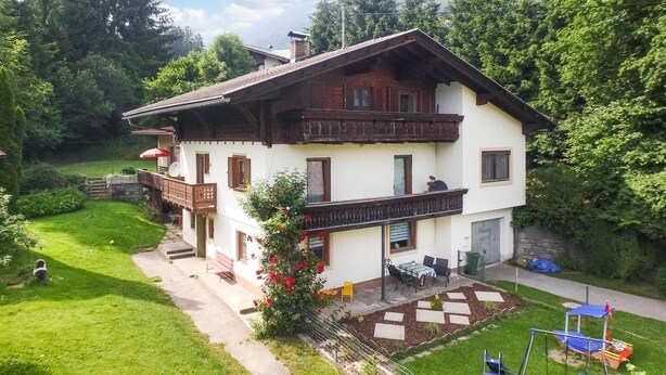 A two-story chalet with a balcony, a garden, and a play area. - Ferienwohnung in Irschen (Irschen)