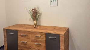 A wooden cabinet with drawers and a vase of dried plants on top. - Ferienwohnung in Irschen (Irschen)