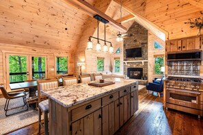 A spacious log cabin interior with a large kitchen, dining area, and a fireplace.