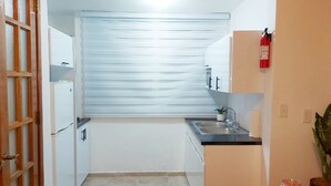 Eine kleine Küche mit Fenster, Spüle und Feuerlöscher.