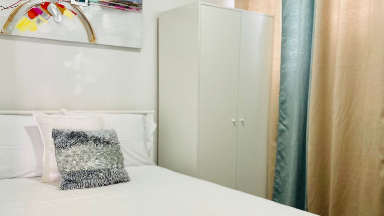 Un dormitorio con cama, armario y cortina.