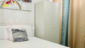 Ein Schlafzimmer mit Bett, Kleiderschrank und Vorhang.