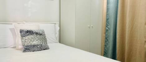 Un dormitorio con cama, armario y cortina.