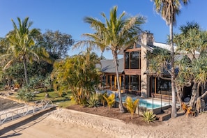 Uma casa moderna com piscina, cercada por palmeiras e um jardim paisagístico.