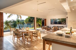 A spacious indoor area with a dining table, chairs, and a kitchen counter. - South Straddie Retreat by Laguna Pacific (South Stradbroke)