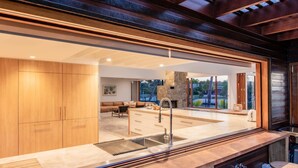 A modern kitchen with a large island, built-in cabinets, and a stone fireplace. - Quiet Island Paradise! (South Stradbroke)