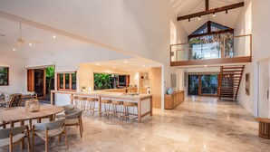 A spacious kitchen with a central island, a dining area with a round table and chairs, and a view of greenery outside. - Quiet Island Paradise! (South Stradbroke)