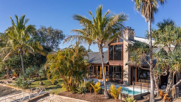 A modern house with a pool, surrounded by palm trees and a well-maintained garden. - Quiet Island Paradise! (South Stradbroke)