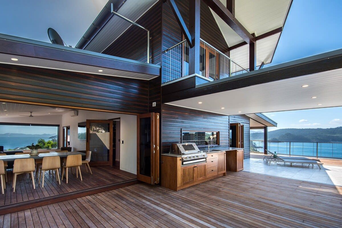 A modern kitchen with a central island, a dining area with a table and chairs, and a view of the ocean.