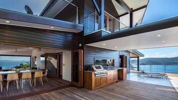 A modern kitchen with a central island, a dining area with a table and chairs, and a view of the ocean.
