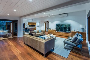 A spacious living area with a sofa, armchair, and a television.