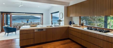 A modern kitchen with wooden cabinets, a large island, and a view of the outdoors.