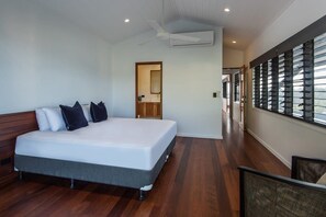 A modern bedroom with a large bed, a ceiling fan, and a view of a balcony. - Horizons - Hamilton Island (Whitsundays)