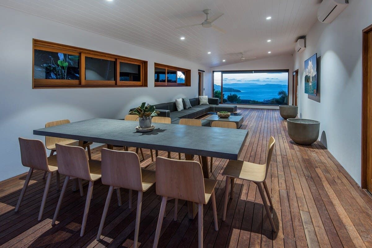 Un intérieur moderne comprenant un coin repas, des sièges et une vue sur la mer.
