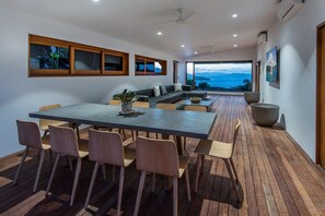 A modern interior with a dining area, seating, and a view of the sea. - Horizons - Hamilton Island (Whitsundays)