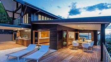 A modern house with a deck, a kitchen, and a dining area.