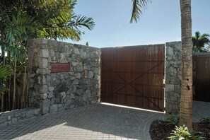 A stone wall with a metal gate, a paved entrance, and a sign that reads 'Pafillion V4'.