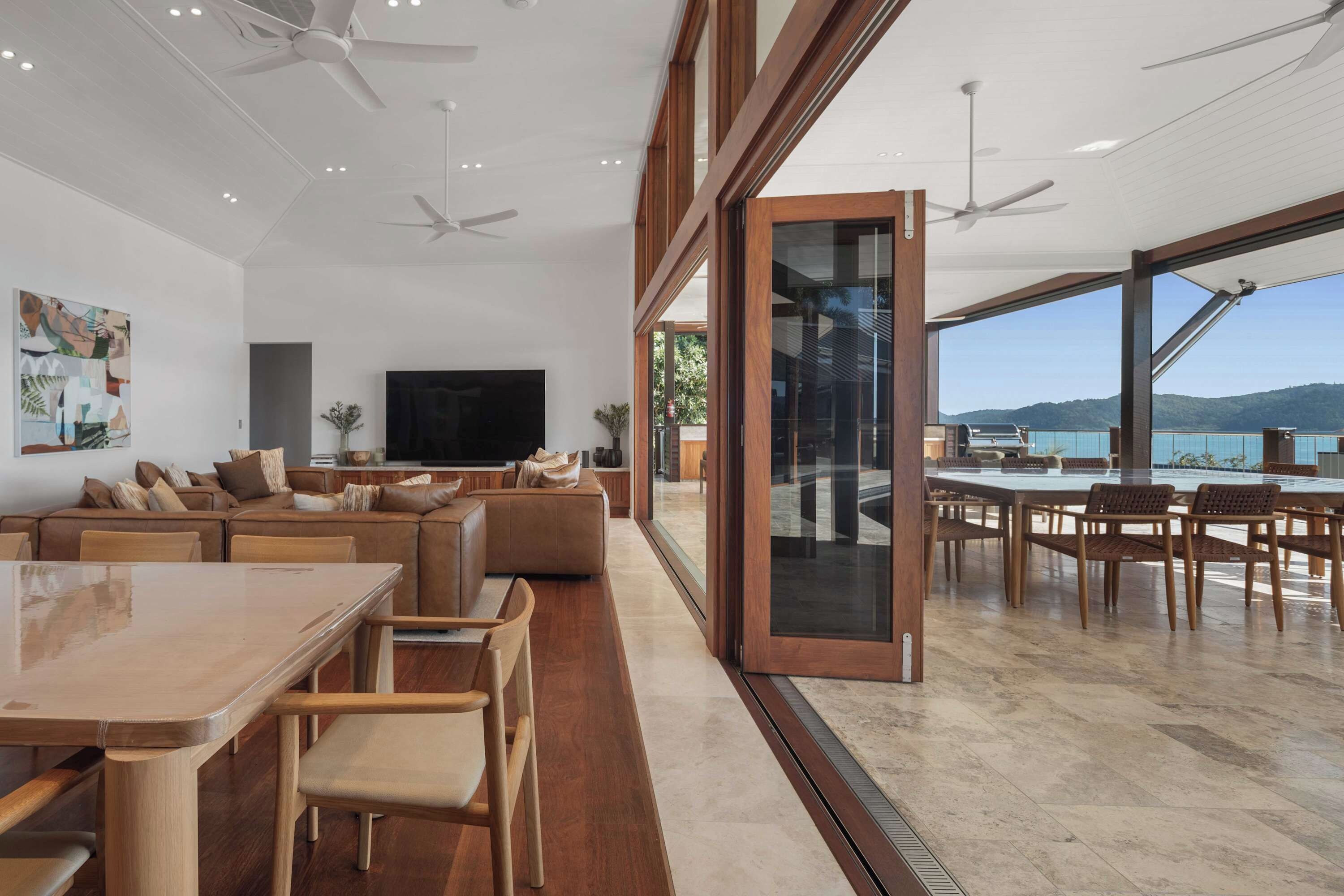 A spacious living area with a large TV, comfortable seating, and a view of the sea.