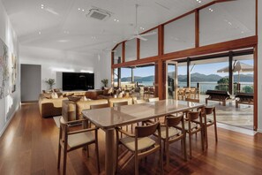 A spacious living area with a large wooden dining table, comfortable seating, and a television.