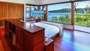 Een slaapkamer met een groot bed, houten meubels en uitzicht op een meer.
