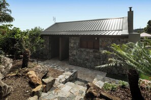 A stone building with a metal roof, a stone staircase, and a small garden area with plants. - Papillon - Hamilton Island (Whitsundays)
