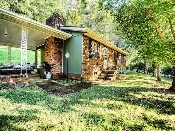 A brick house with a covered porch and a barbecue area.