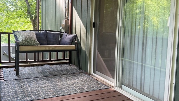 A covered porch with a wooden bench, a rug, and a sliding glass door. - Low Key Living Hideaway (Lavalette)