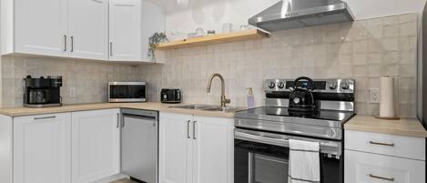 A modern kitchen with white cabinets, a stainless steel stove, and a microwave.