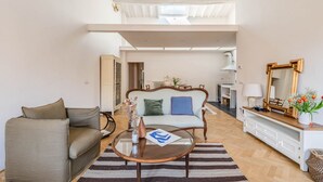 A living room with a sofa, a coffee table, a checkered sofa, a mirror, and a view of a kitchen. - Apartments Florence - Sprone Terrace (Firenze)