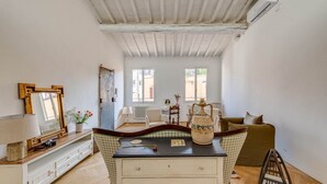 A room with a wooden ceiling, a white wall, a window, a sofa, a table, and a cabinet. - Apartments Florence - Sprone Terrace (Firenze)