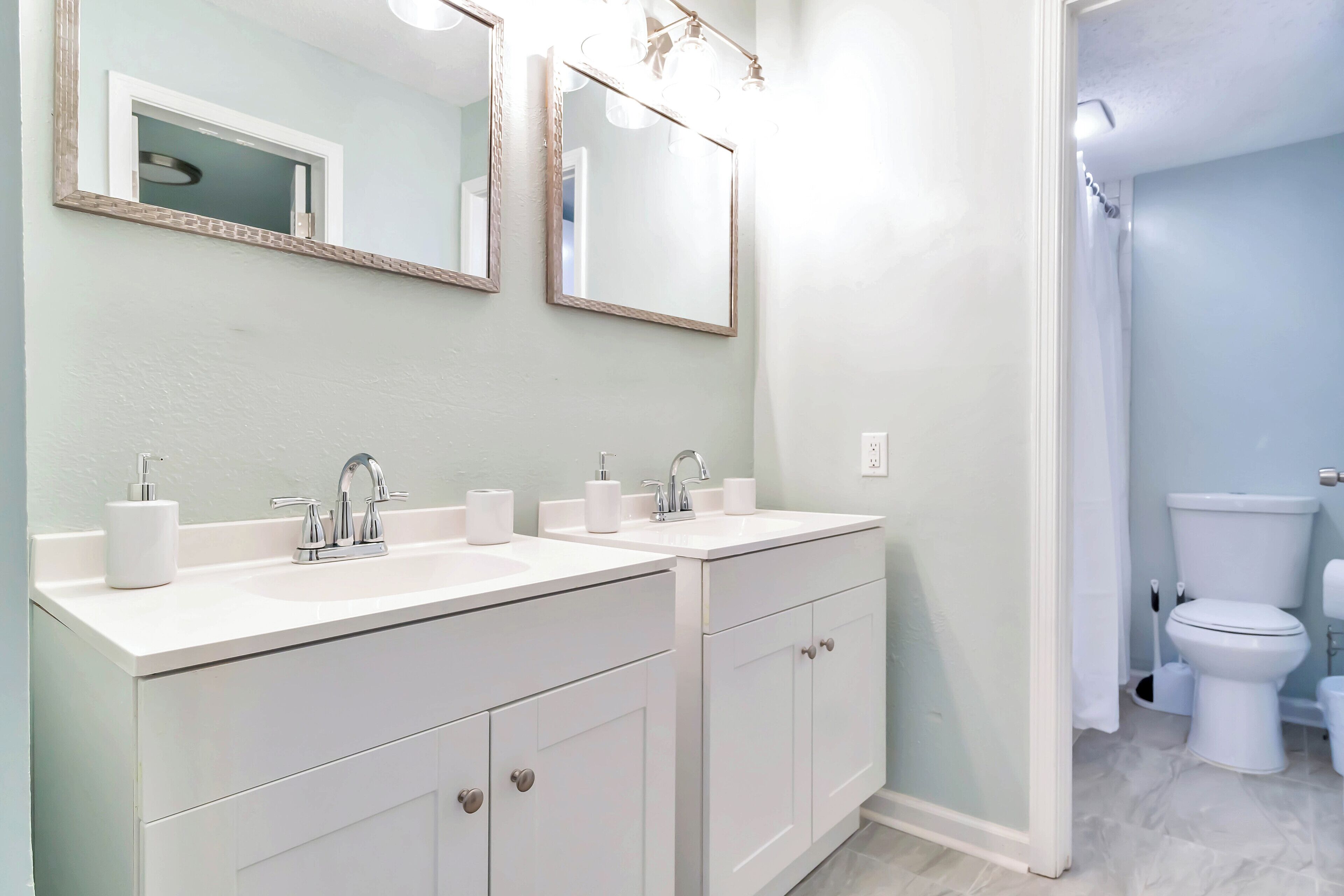 A bathroom with two sinks, a mirror, and a toilet.