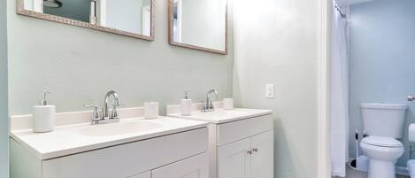 A bathroom with two sinks, a mirror, and a toilet.