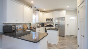 Una cocina moderna con gabinetes blancos, electrodomésticos de acero inoxidable y una isla central.