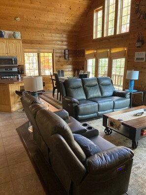 A log cabin interior with a leather sofa, dining table, and kitchen area. - Little Cottage On Prairie - Prairie Lake That Is!!! (Cameron)